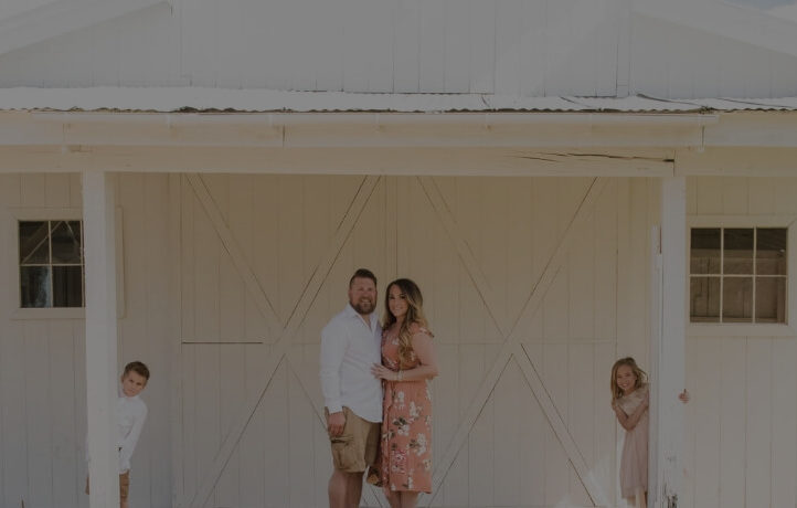 A portrait of a young family posed outside.