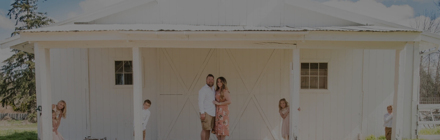 A portrait of a young family posed outside.