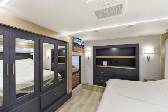 Spacious and modern bedroom inside the 2025 Heartland Cyclone 4215, featuring a large bed, stylish cabinetry, and ambient lighting.