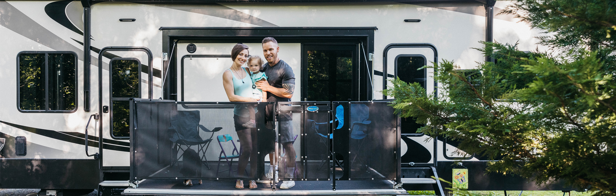 A couple holding a small child on the patio of an RV.