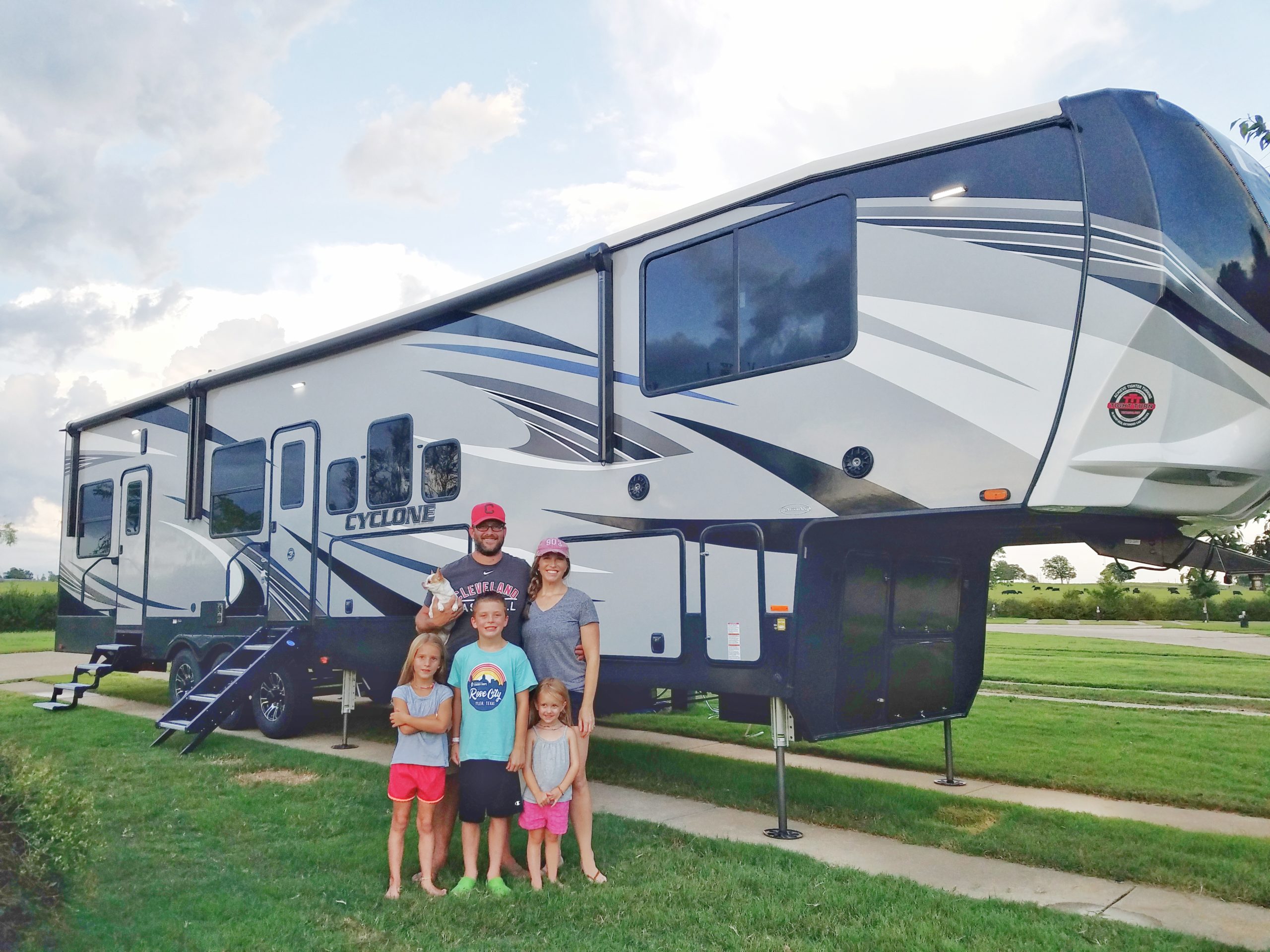 A family posed in front of a Heartland Cyclone travel trailer RV. 
