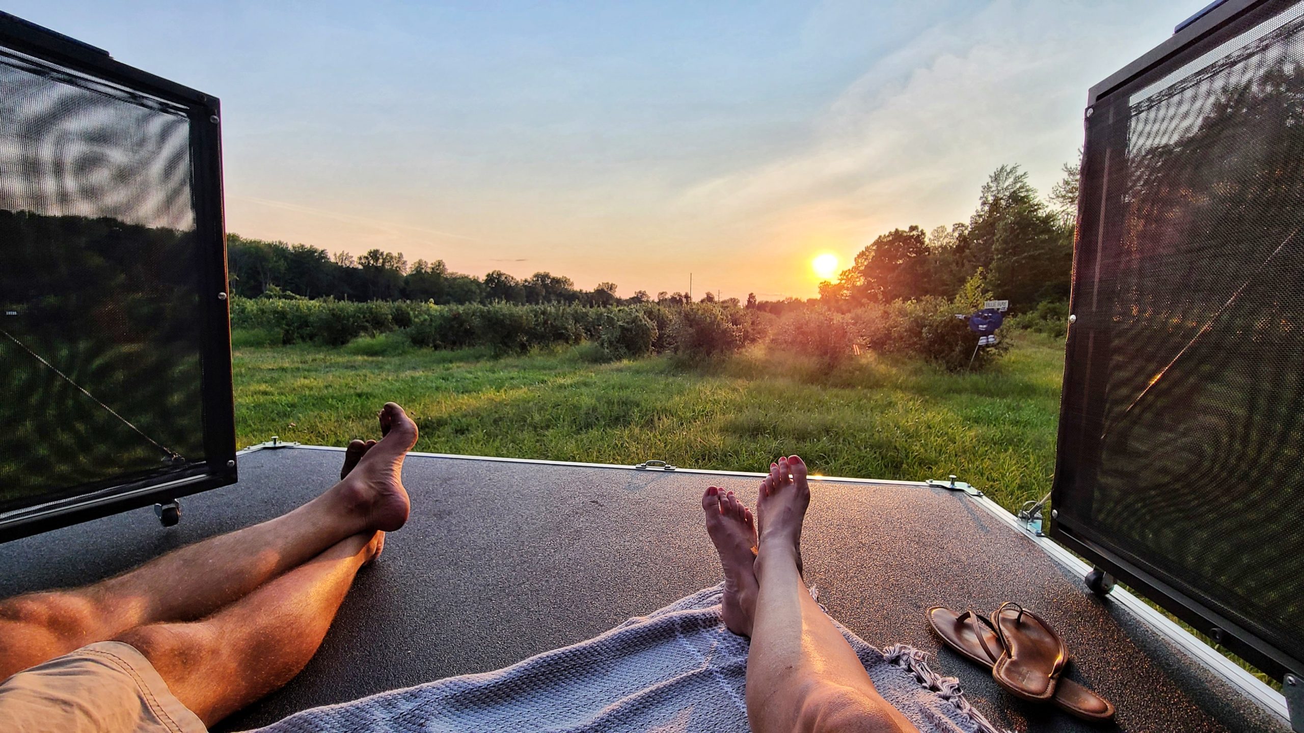 Two adults watching the sun set from the back patio on a toy hauler RV.