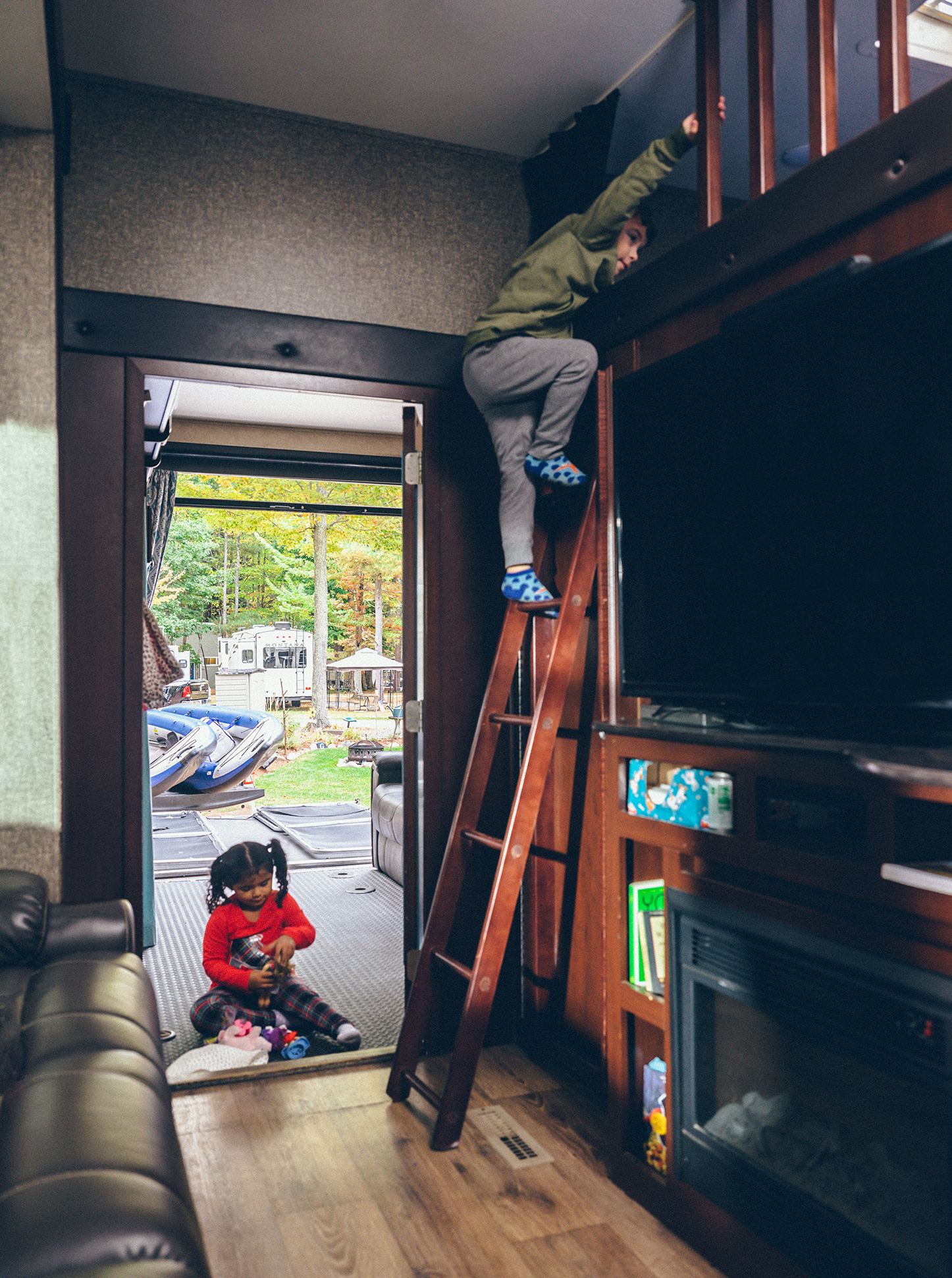 Two small kids playing inside the toy hauler. 