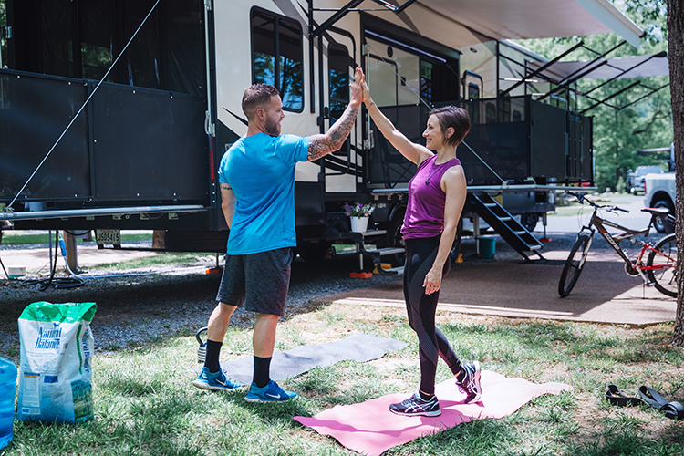 A man and a woman high-fiving after completing an outdoor workout on the road.