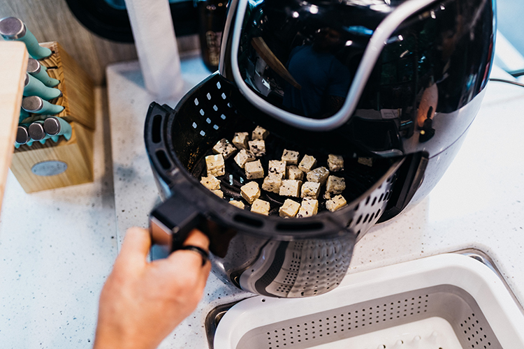 A top-down photo of tofu cubes in an air fryer. 