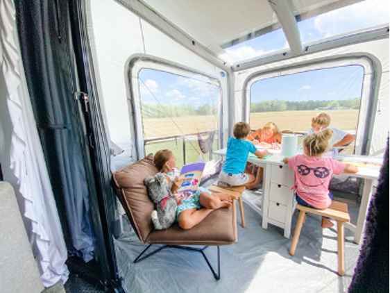 Four kids on an RV patio at a desk. 