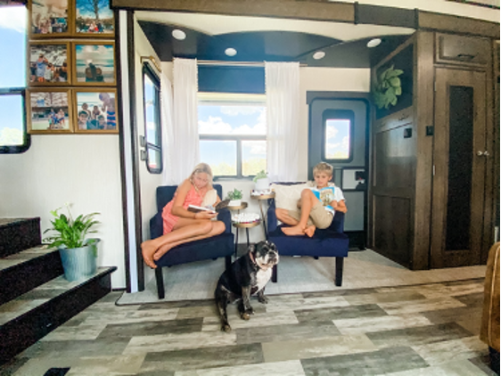 Two kids and a ddog in the living area of an RV; the kids are reading. 