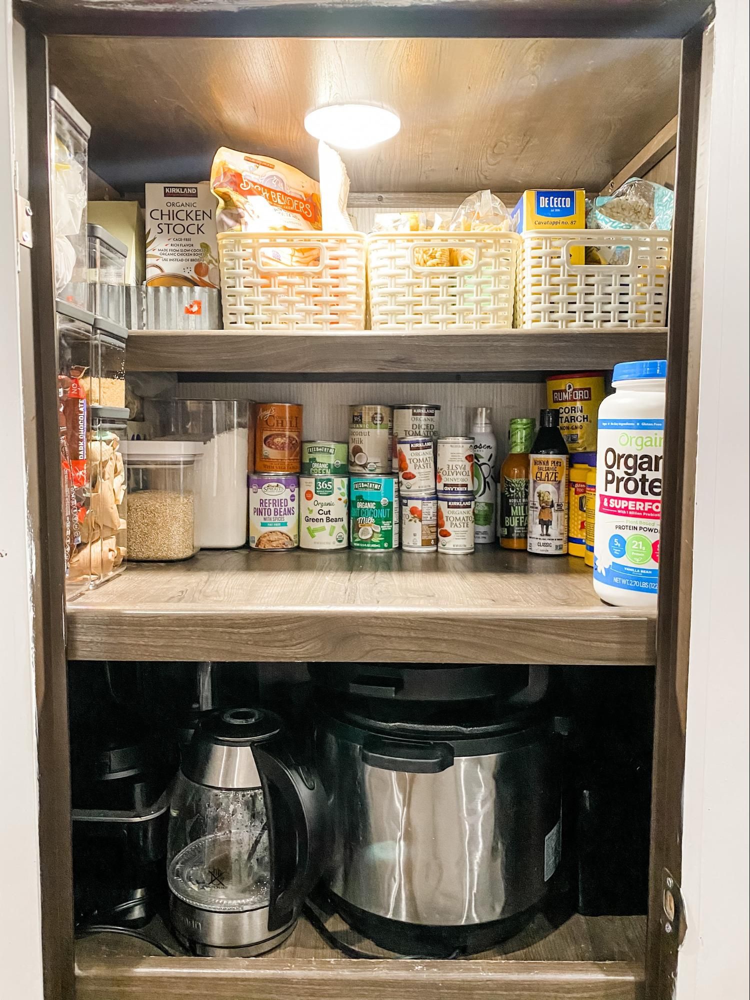 A neatly organized RV pantry showing plastic baskets grouping like items.