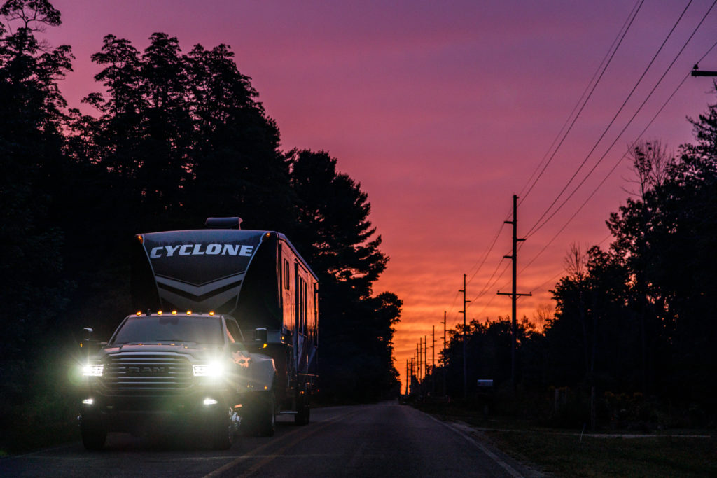A Cyclone RV towed behind a truck at sunset.