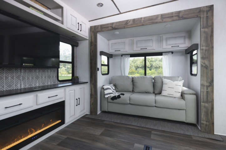 Elegant living room inside a Bighorn Traveler fifth wheel, featuring plush seating, a modern fireplace, and stylish décor.