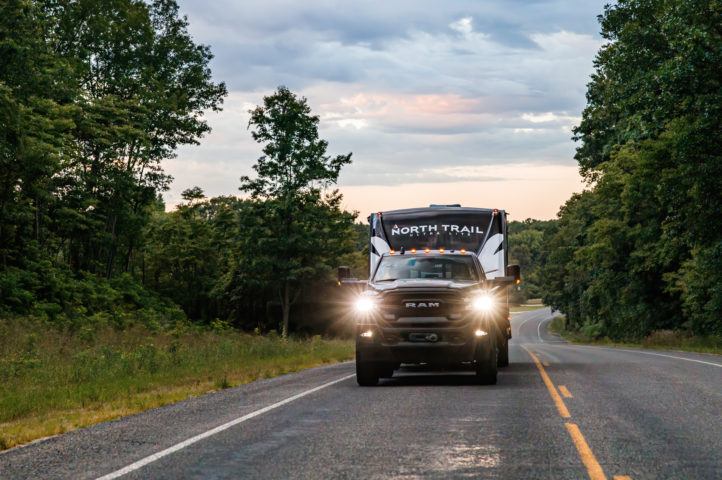 A North Trail travel trailer towed by a truck on the road.