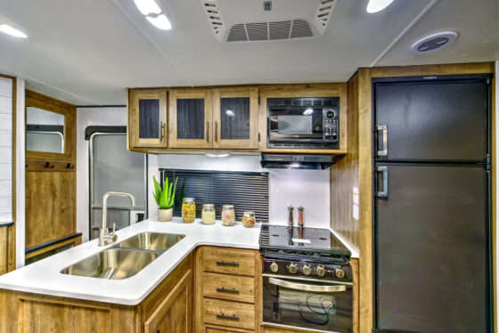 Compact and functional kitchen in a Pioneer travel trailer, featuring modern appliances and ample storage space.