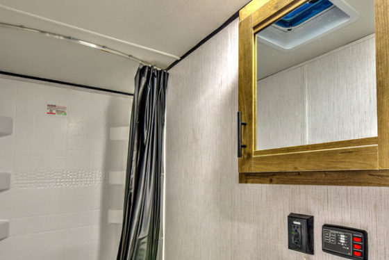 Compact bathroom in a Pioneer travel trailer, featuring a toilet, sink, and shower.