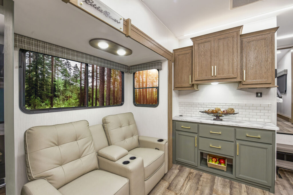 The image showcases the 2025 Eddie Bauer EBF 2500RK travel trailer, highlighting its sleek and modern kitchen area. The kitchen features elegant cabinetry and stylish countertops, complemented by high-quality appliances, including a refrigerator and stove. The well-lit space is designed for both functionality and aesthetics, making meal preparation a joy. A spacious sink is conveniently placed for easy access, and the open layout ensures a seamless flow between the kitchen and the adjoining living area. This inviting setup makes the EBF 2500RK an ideal choice for families and adventure-seekers looking to enjoy the comforts of home while on the road.